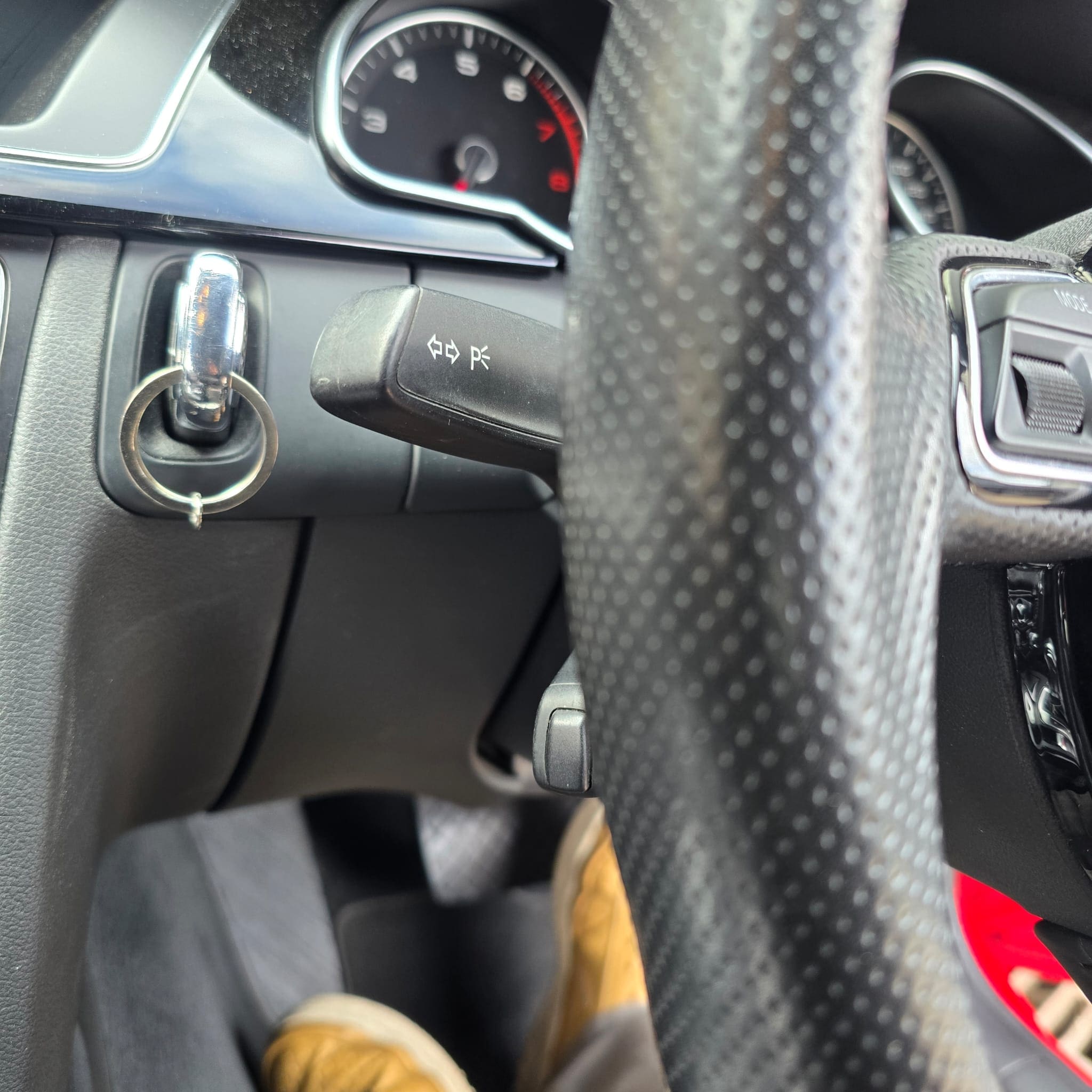 Close-up of Audi A5 steering column area showing OEM cruise control hardware installed