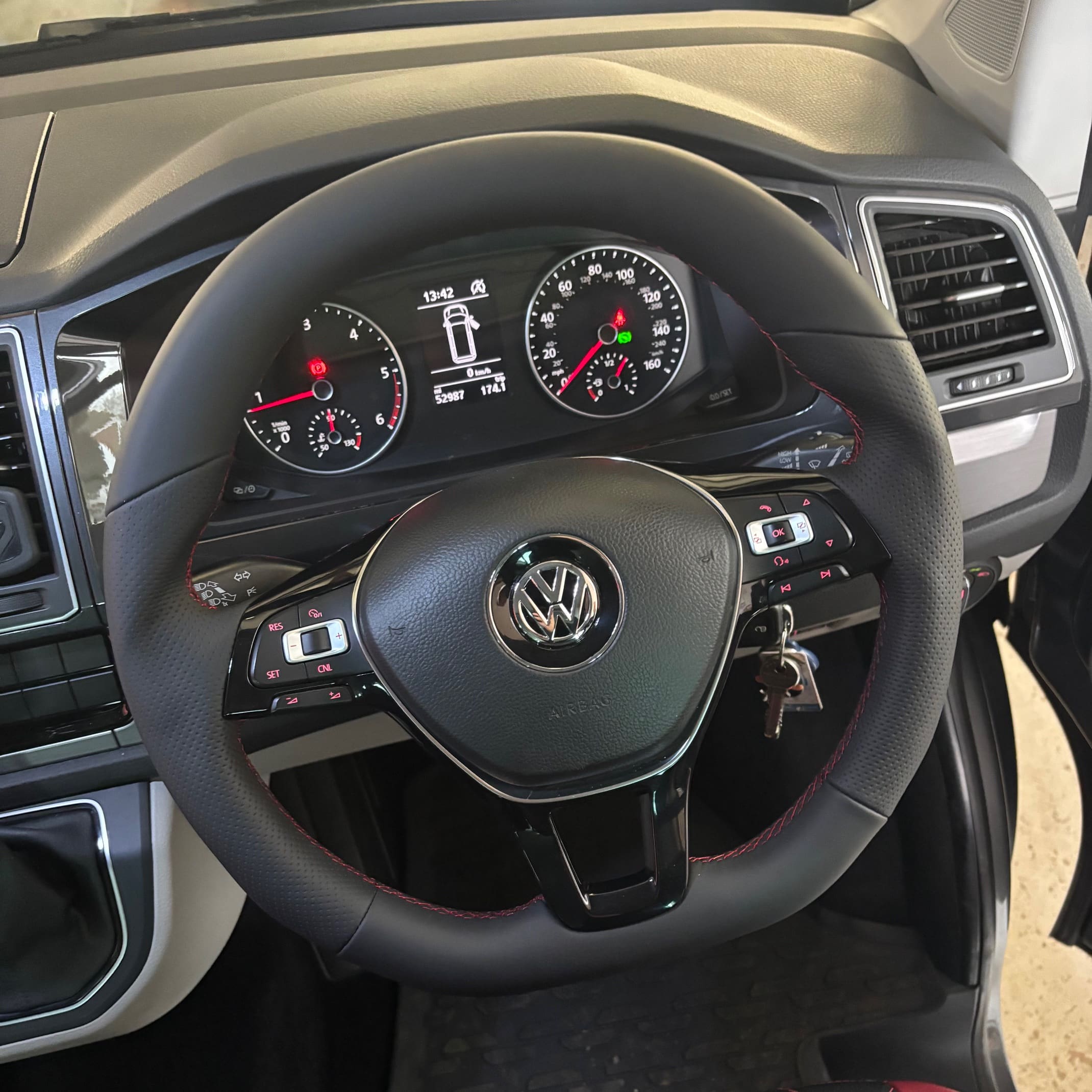 Completed steering wheel retrim showing red stitching aligned with seat stitching theme