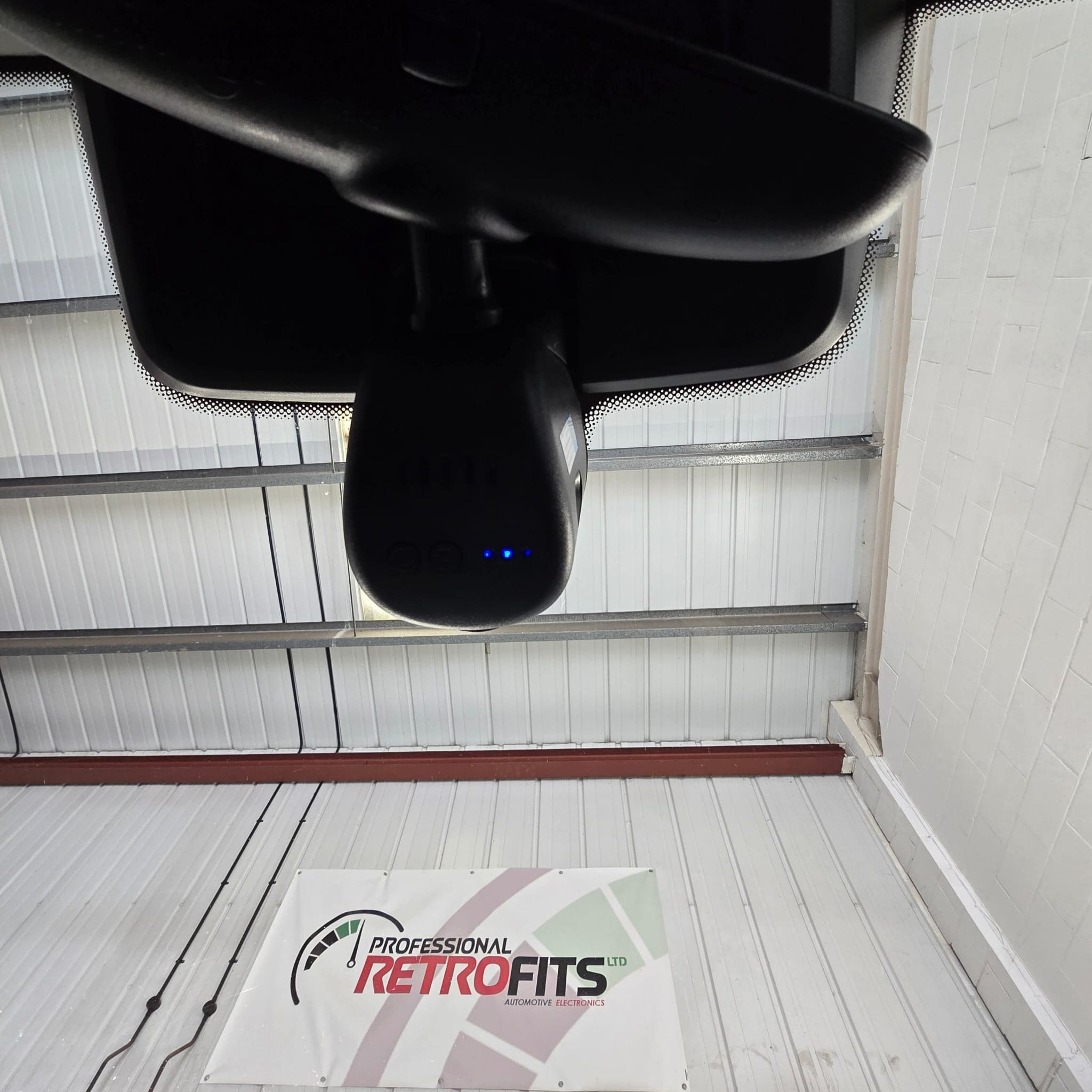 Close-up view of Porsche 911 mirror trim area showing the dash cam installation designed to stay out of sight