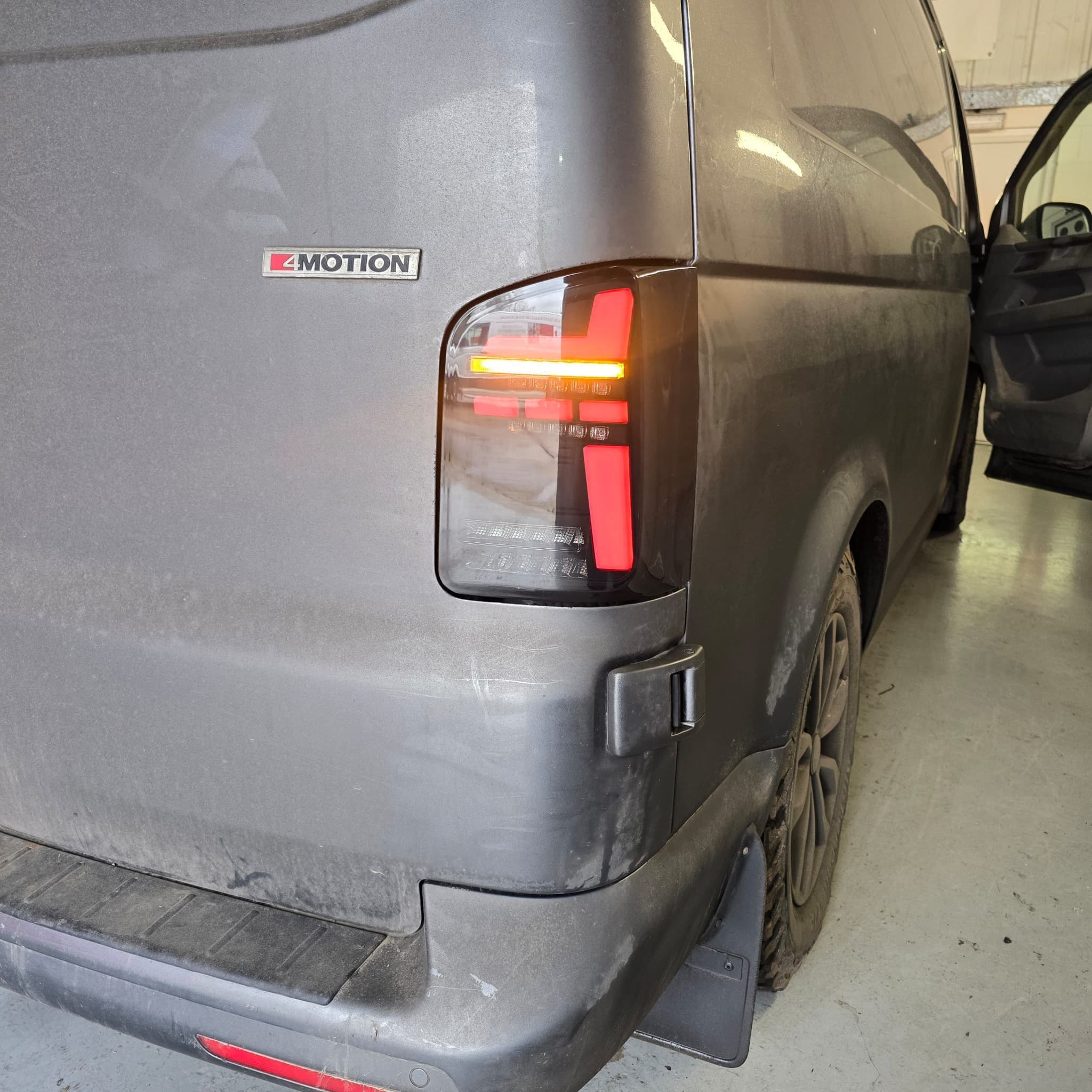 VW T6.1 rear view after Transporter HQ tail light installation showing smoked LED finish on dark blue paint