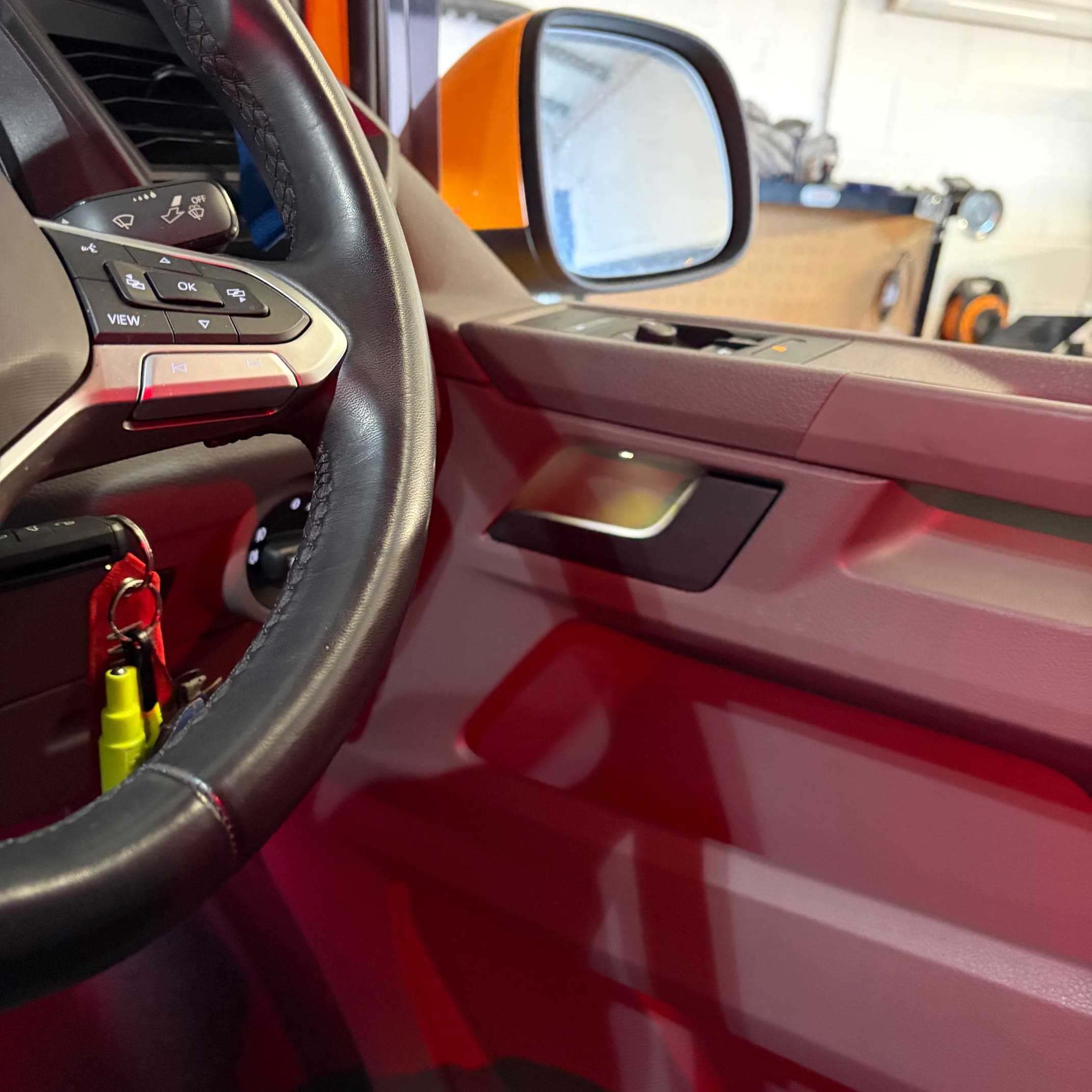 VW Transporter in the workshop during red ambient lighting fitment to the door card and footwell